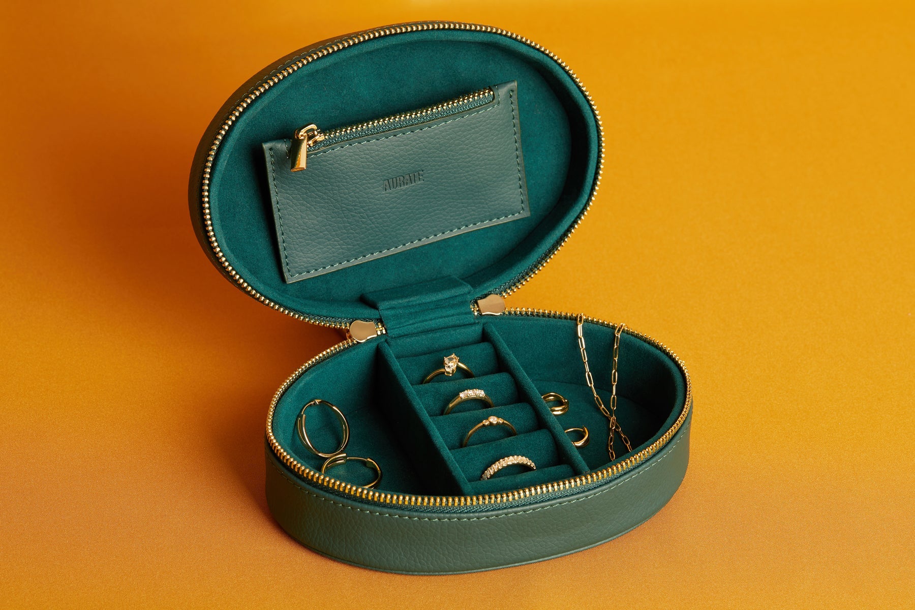 A green jewelry box containing rings and other jewelry