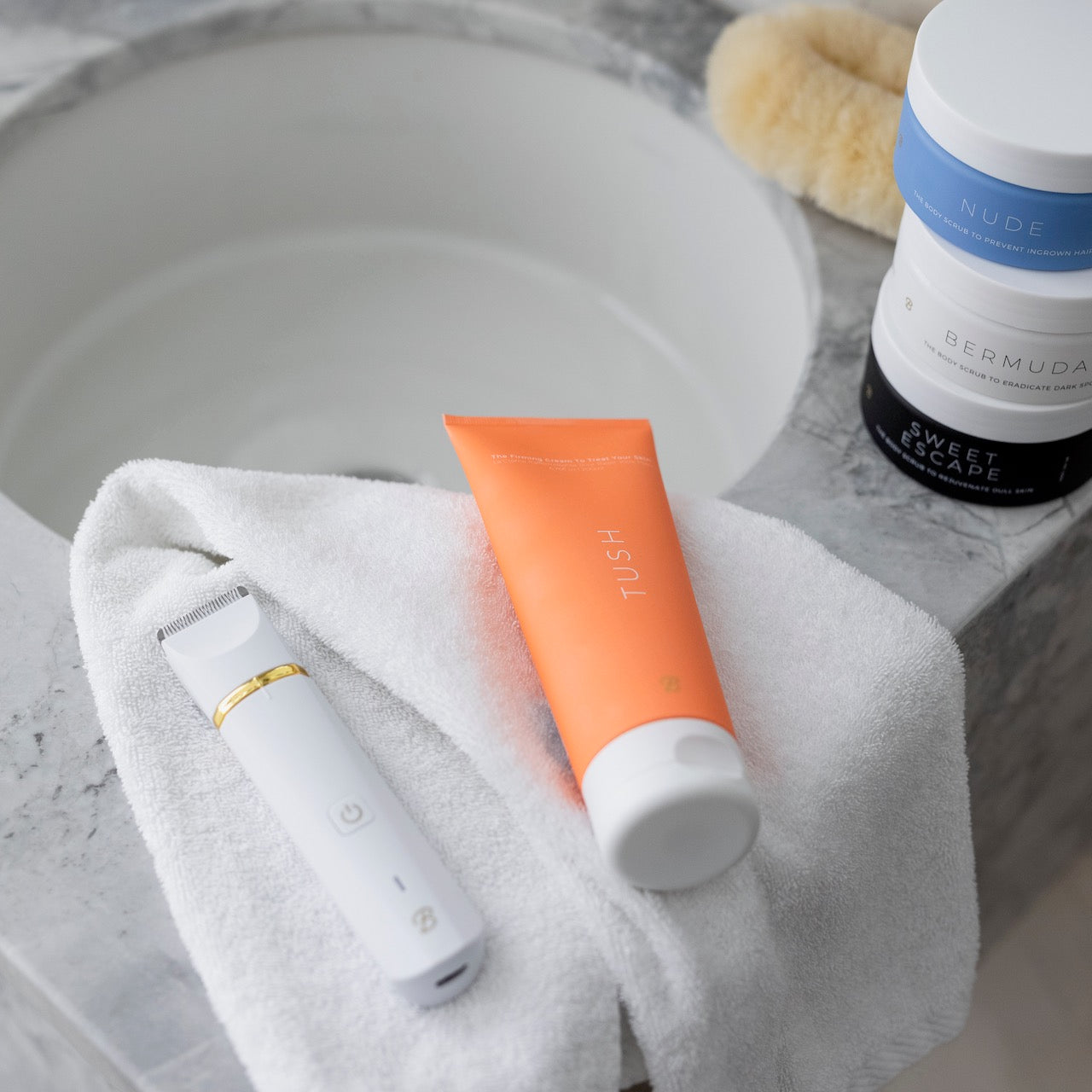 Tube of Tush cream and a trimmer by Bushbalm backdropped by a bathroom counter.