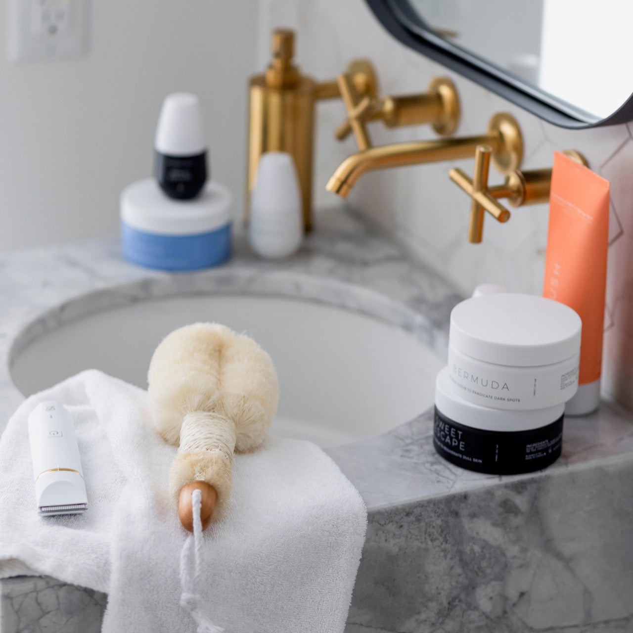 A selection of skincare products from Bushbalm along with its dry brush and trimmer on a bathroom counter.