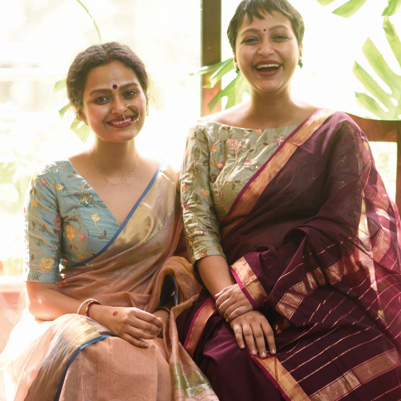 Sujata in a rose-colored saree, and Taniya in a maroon saree.