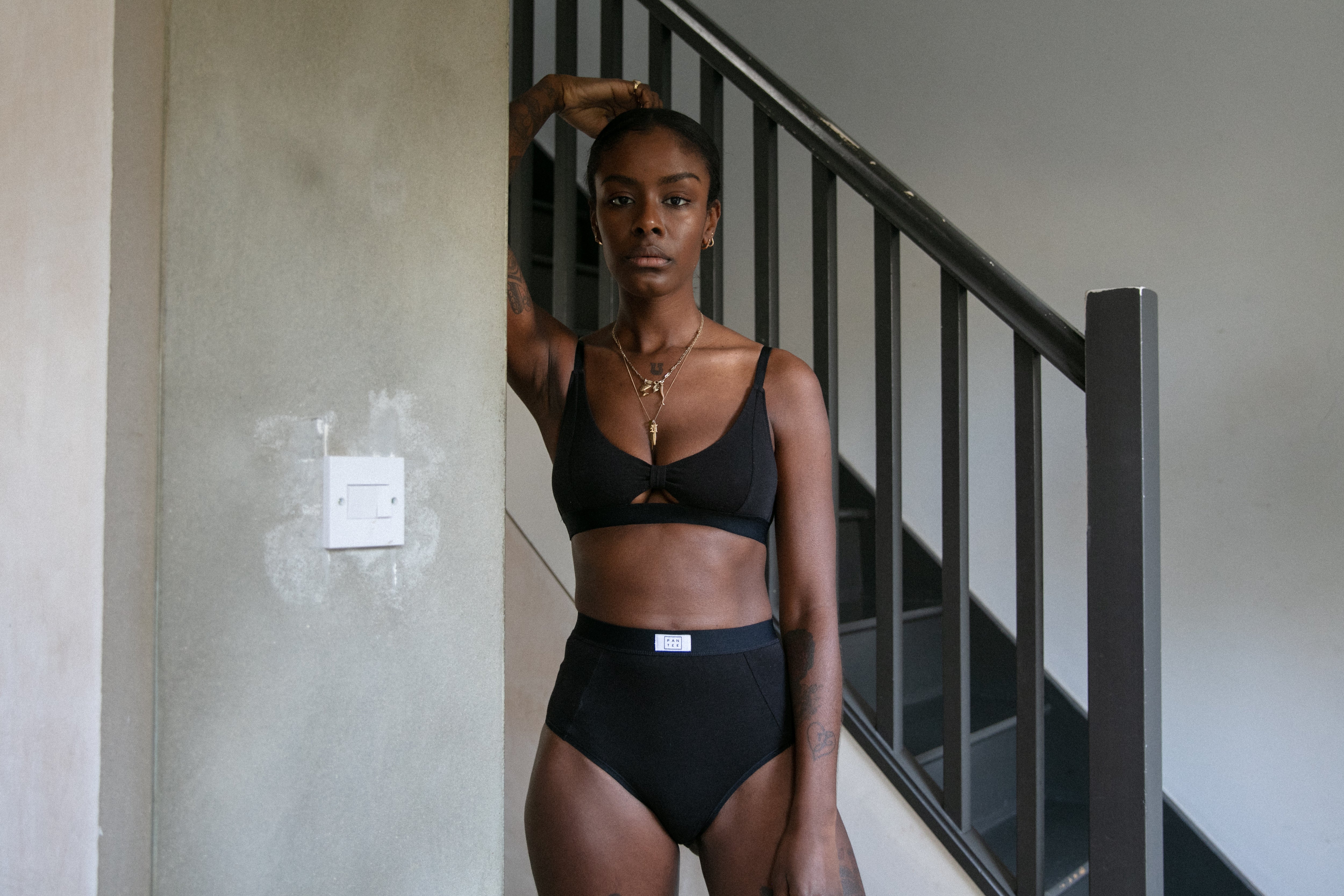 A model posing in front of a staircase wearing a black Pantee set