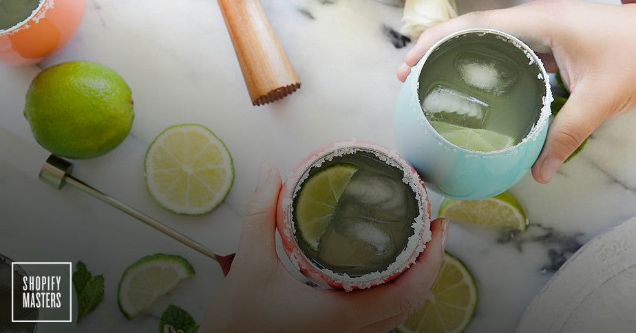 Overhead shot of two hands clinking drinks with ice and lime wedges inside the glass.