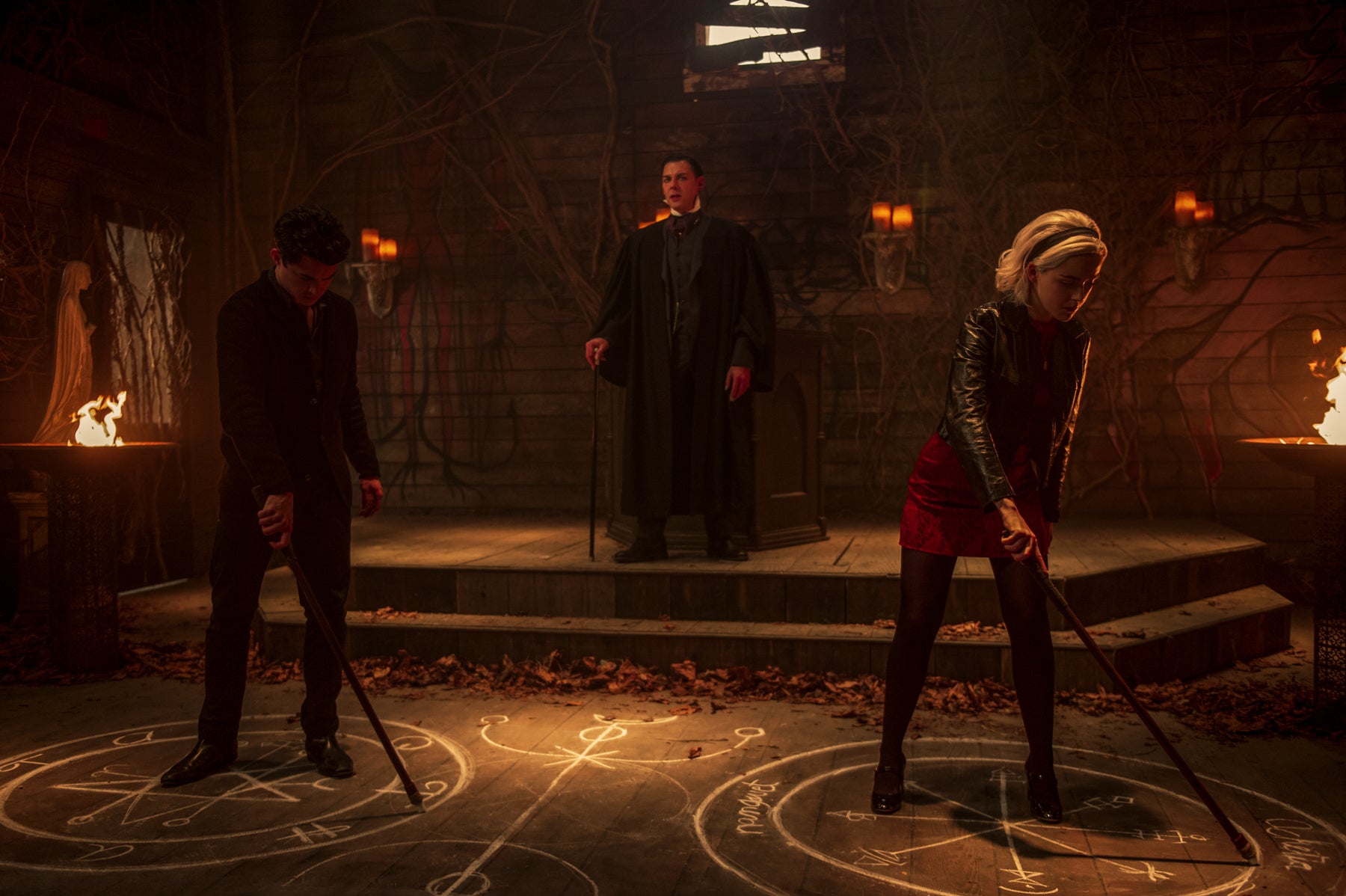 Sabrina Spellman and Nick draw symbols on the ground during a match for Top Boy in a scene from Chilling Adventures of Sabrina.