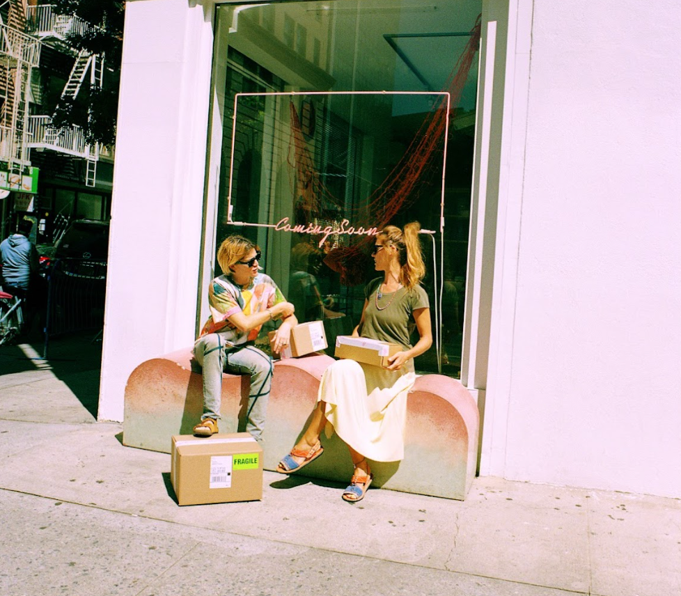 Coming Soon founders sitting in the window in front of their shop