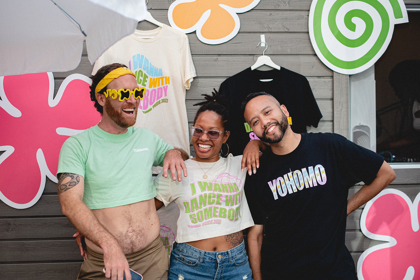 Phil, Armand, and a friend posing at an outdoors event while wearing Yohomo merchandise