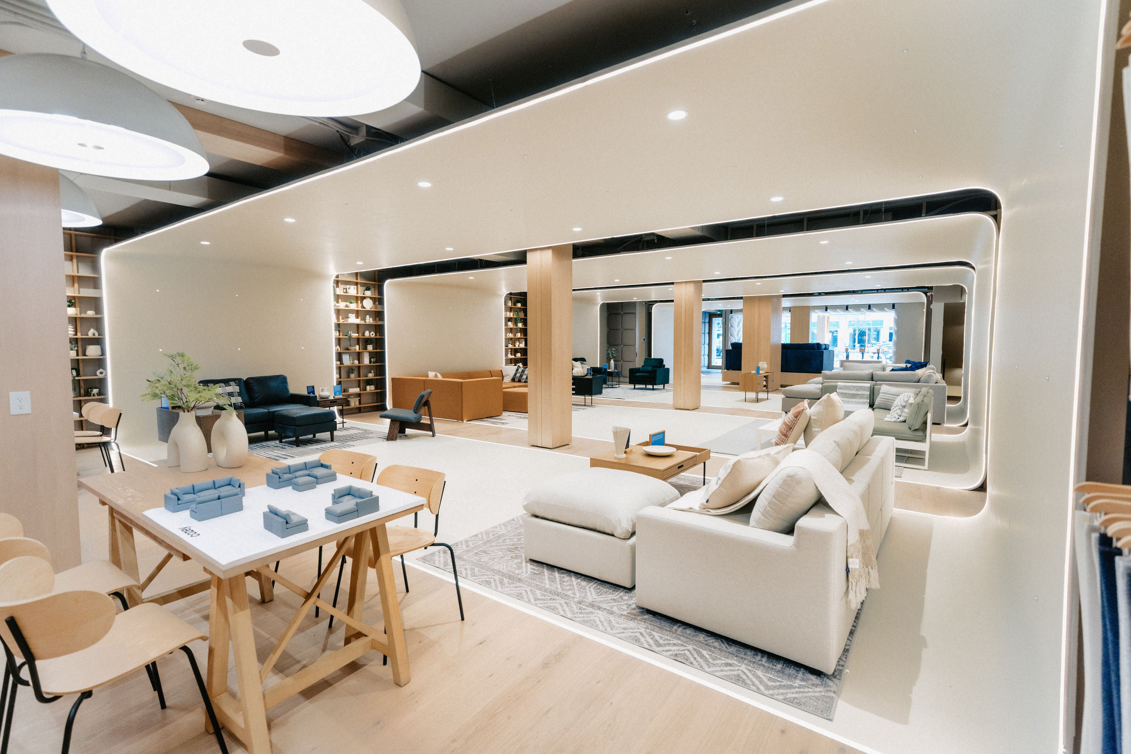 Cozey retail store showroom with couches and tables attractively arranged on rugs under high ceilings with good lighting.