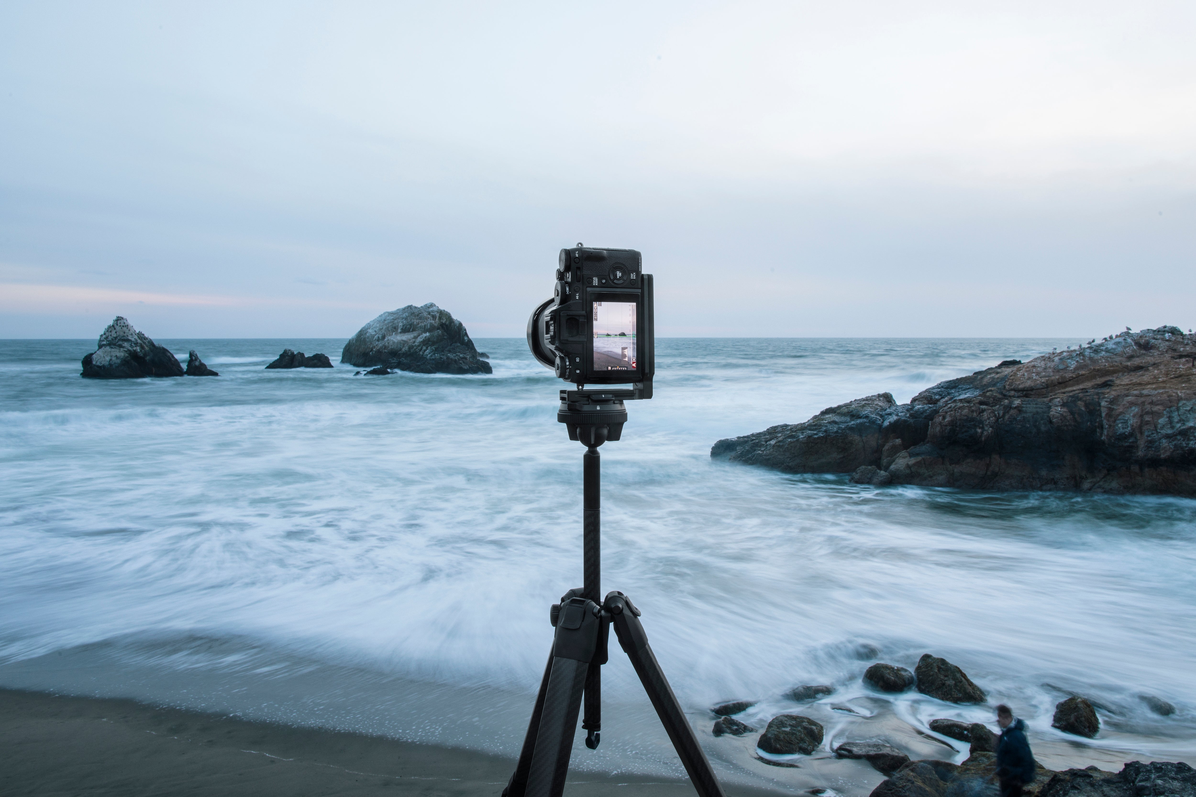 A camera on a tripod in front of an oceanscape. 
