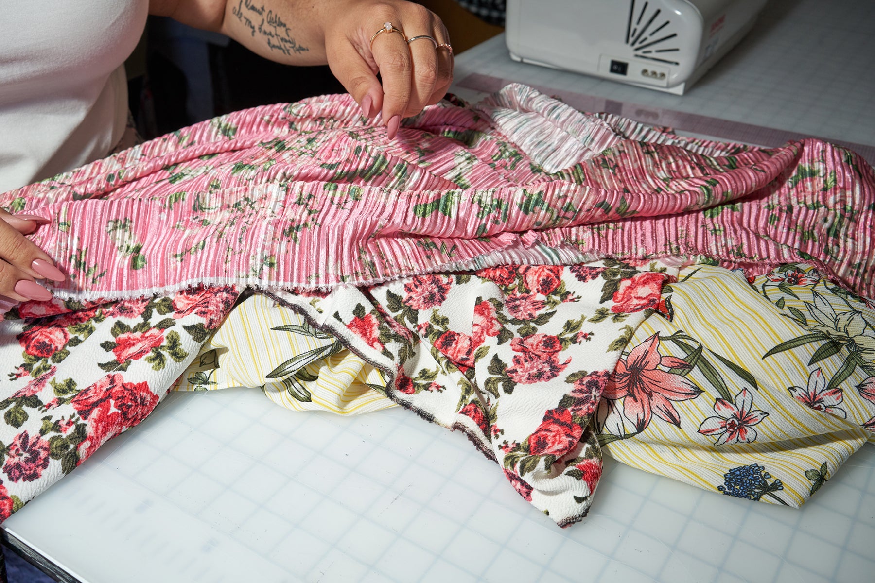 Close up of plus fashion designer Ashley Nell Tipton's hands, working with pink, floral fabric.