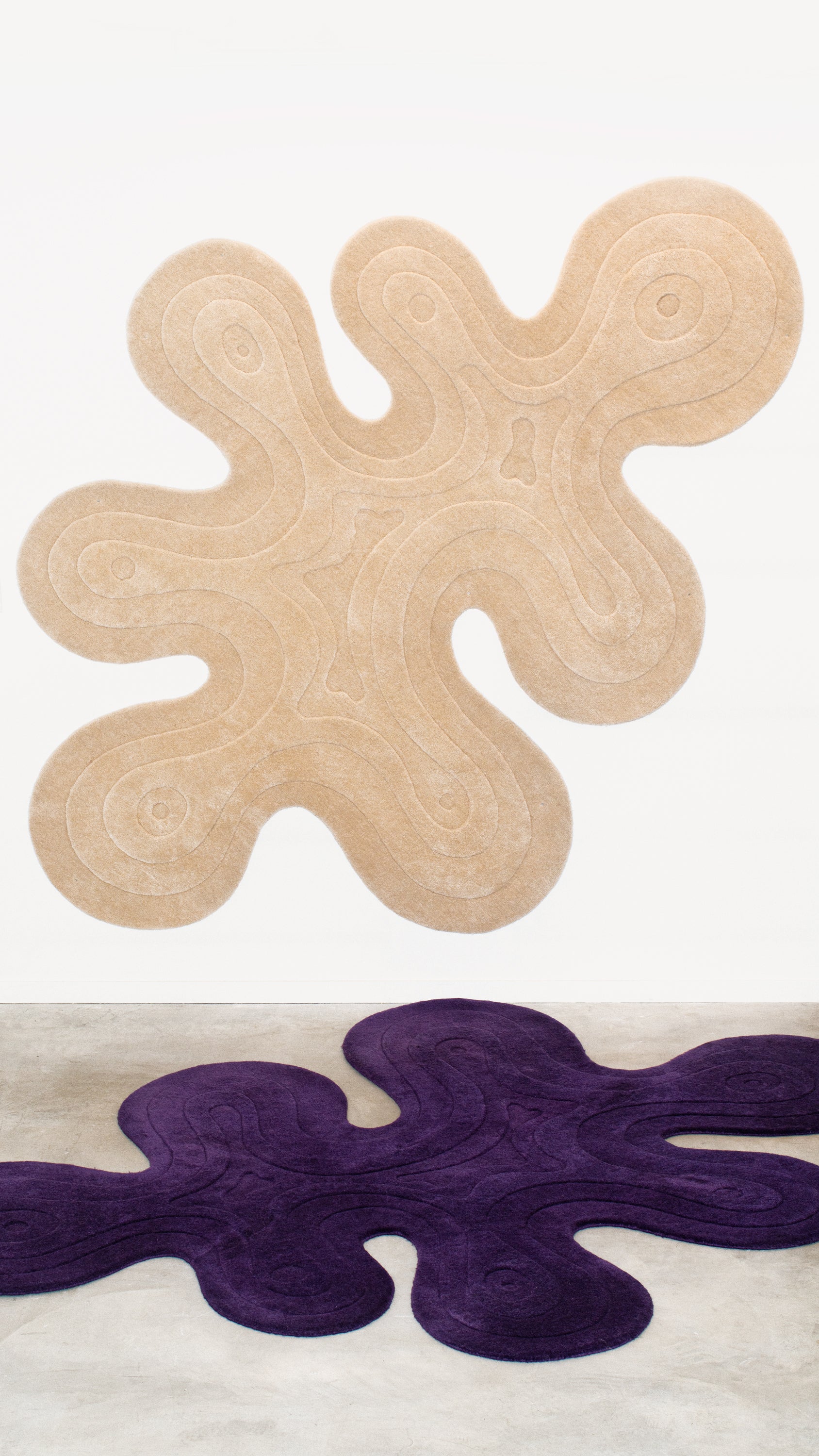 The Dune Rug in color ecru above the Dune Rug in a dark purple color. 