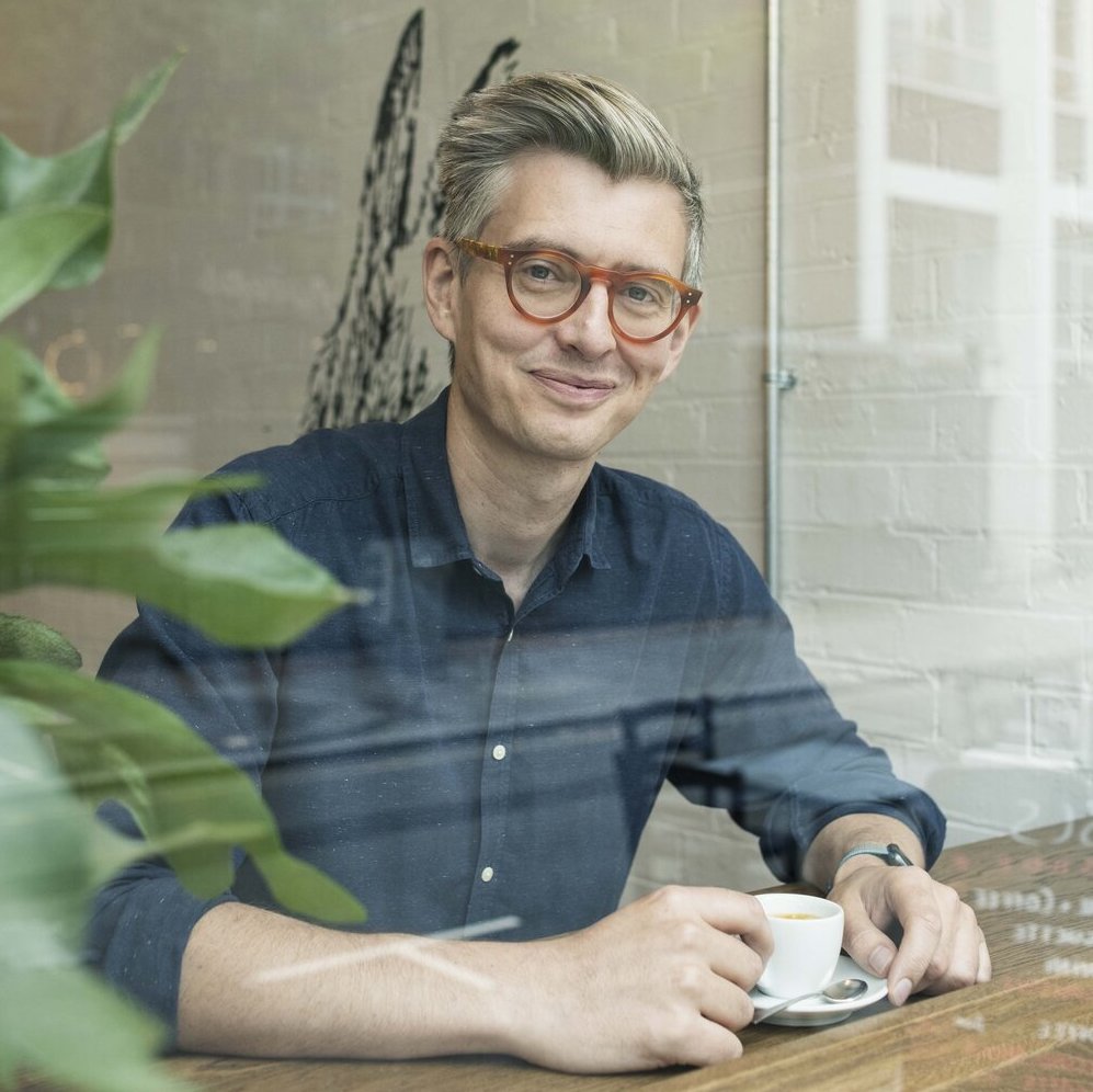 James Hoffmann in a blue dress shirt enjoying a cup of coffee at Prufrock Coffee in London. 