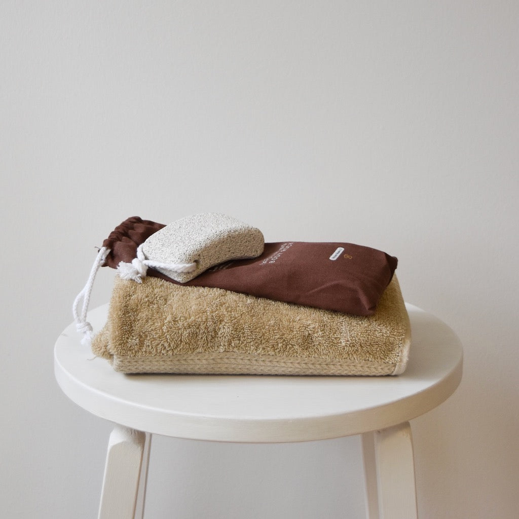 A body stone along with a towel on top of a white stool.