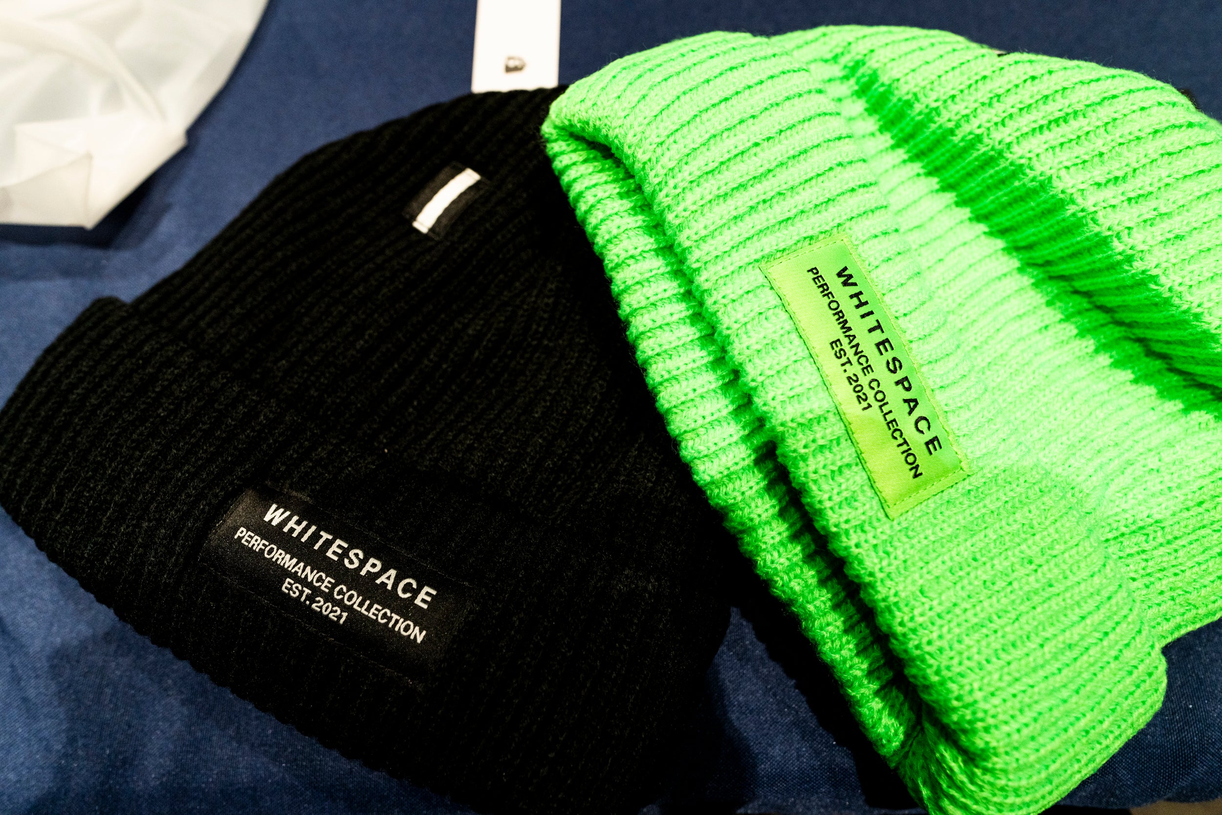 A black and a bright neon green beanie from the limited edition WHITESPACE and Shopify collaboration.