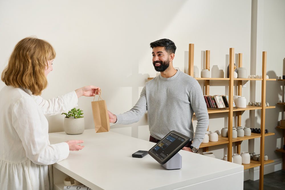 A South Asian shopper picks up an online order from a store clerk