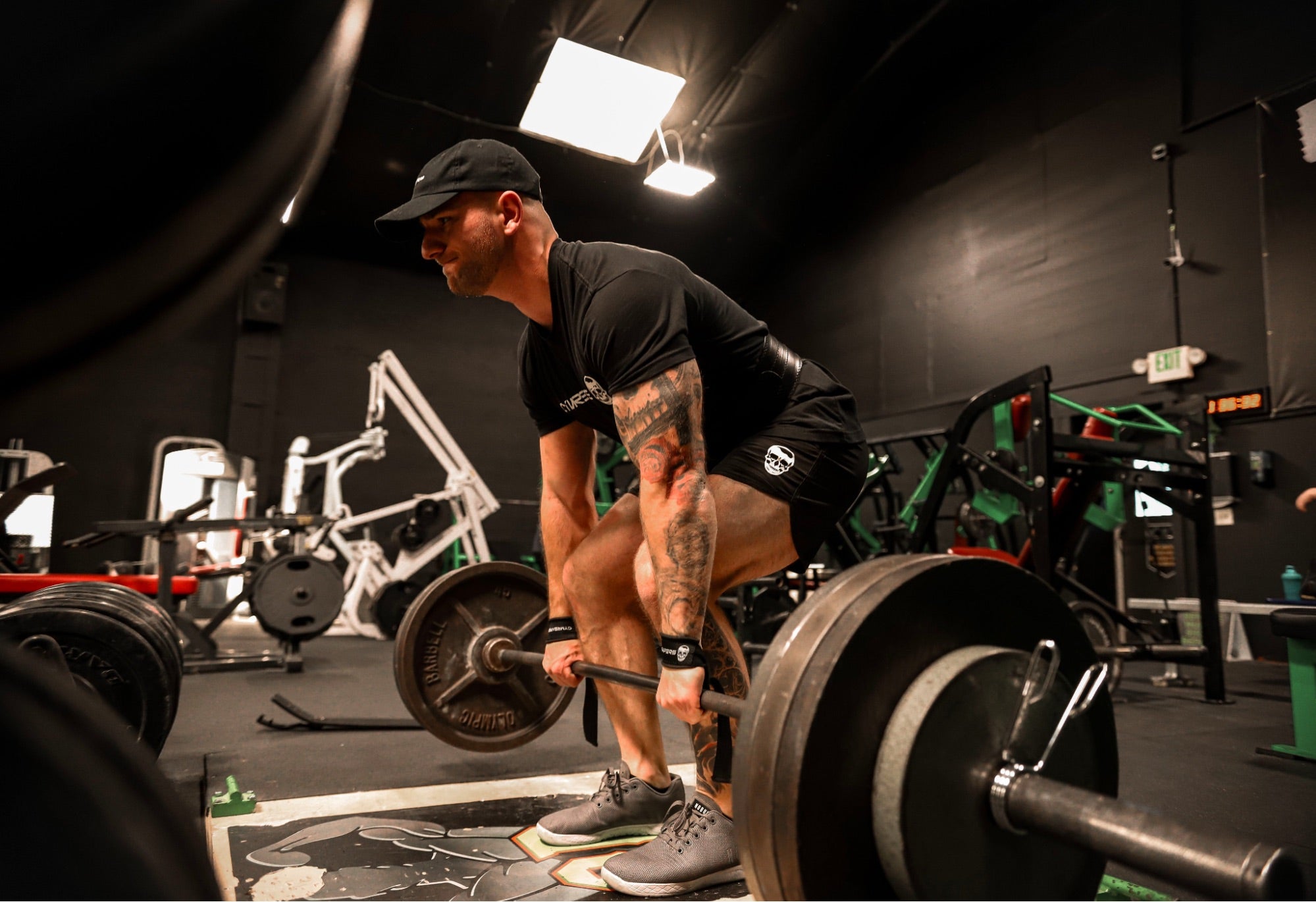 A gym goer wearing all black attire about to power lift some weights. 