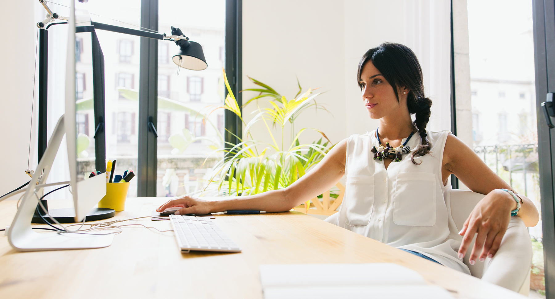 Image of a woman sitting at a desk browsing the internet to find out who owns a domain