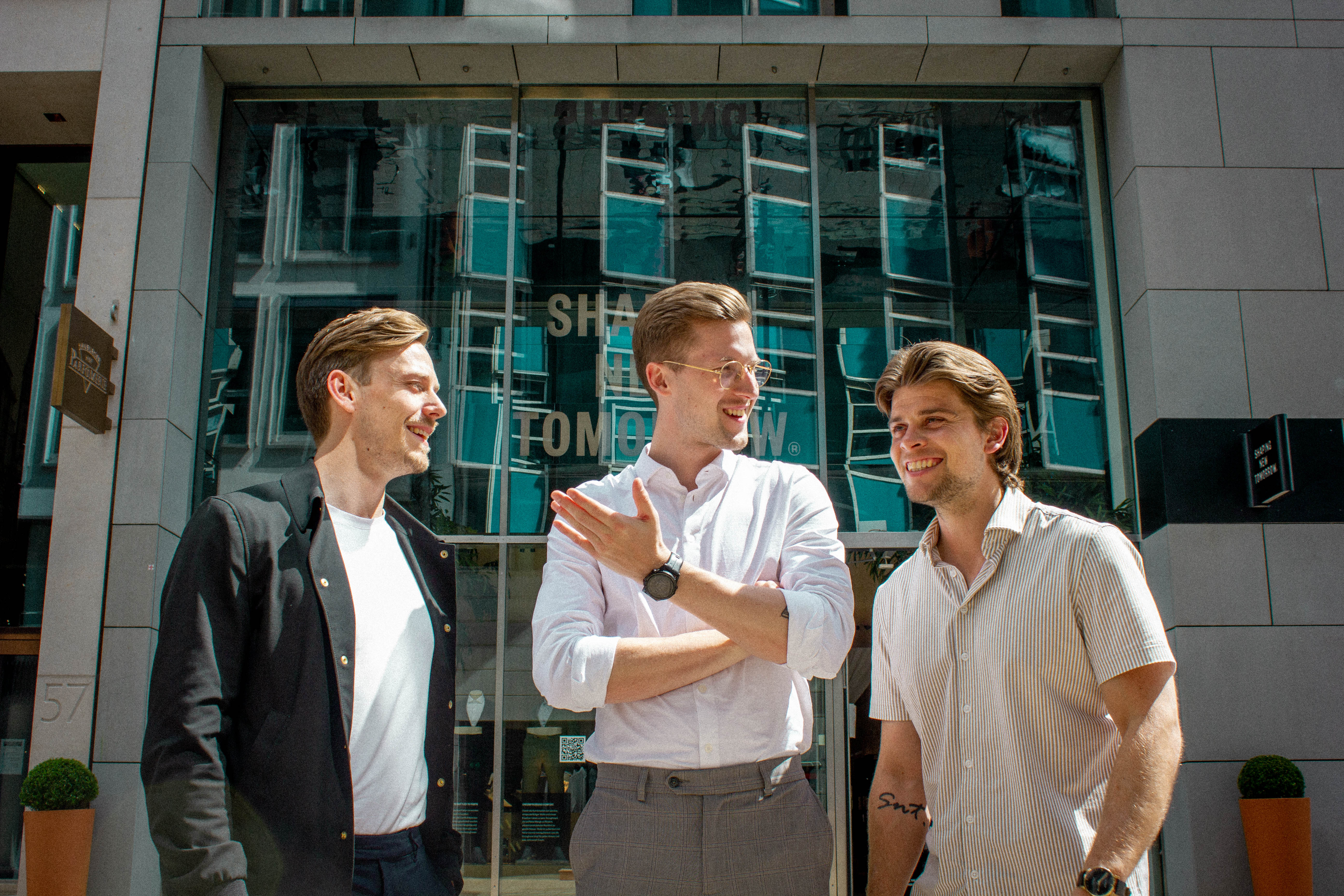Christian Aachmann(left), Kasper Ulrich (center), and Christoffer Bak (right) stand in front of a Shaping New Tomorrow store. 