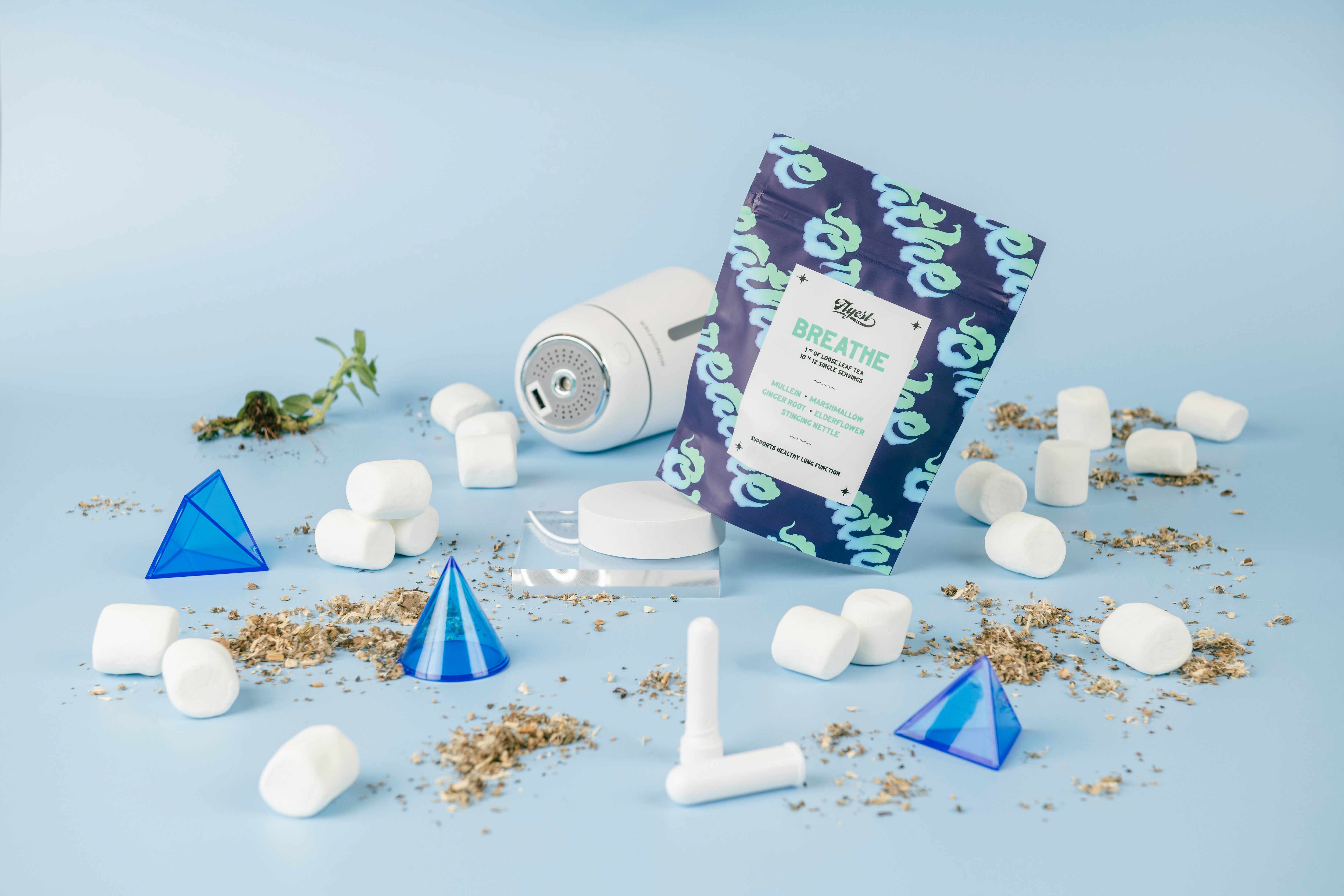 a bag of breathe tea, surrounded by marshmallows, asthma devices, blue triangles, and actual tea leaves.