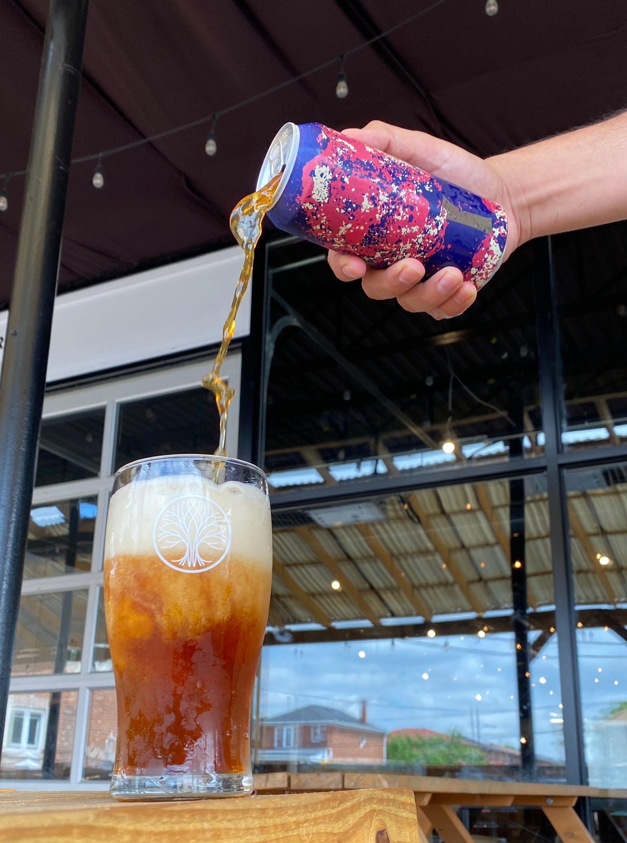 A hand pours Lost Craft beer into a tall glass. 