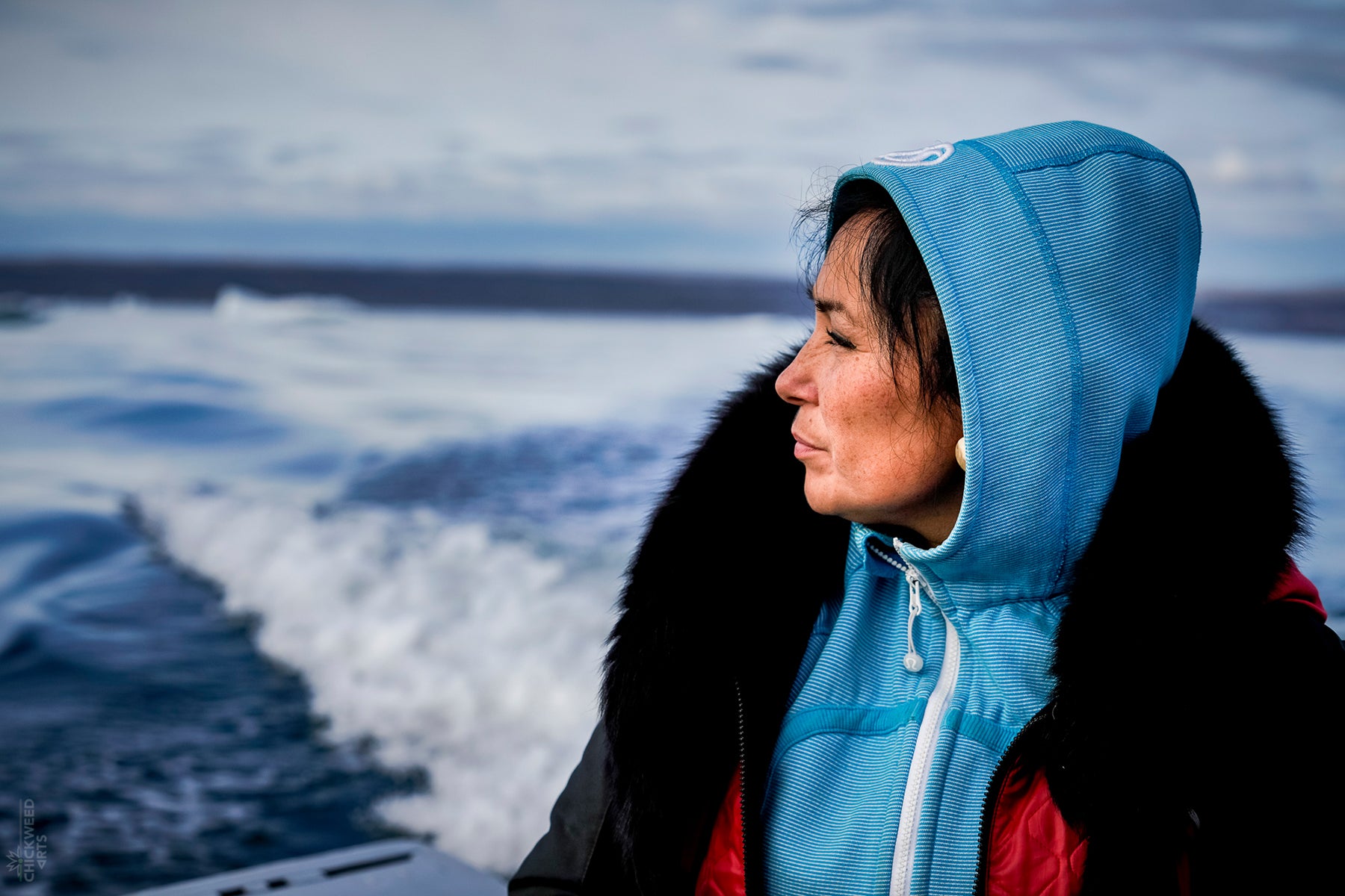 Photograph of Bernice Clarke on a boat in Nunavut staring out peacefully at the ocean.