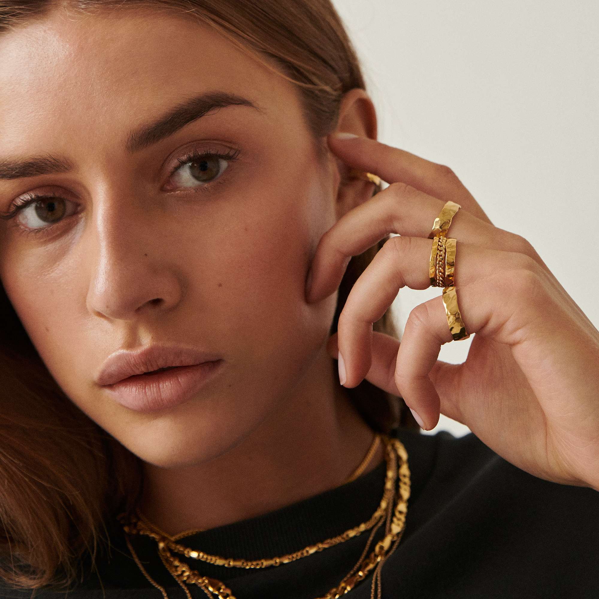 A model in a black shirt wearing multiple necklaces and rings by Camille Brinch. 