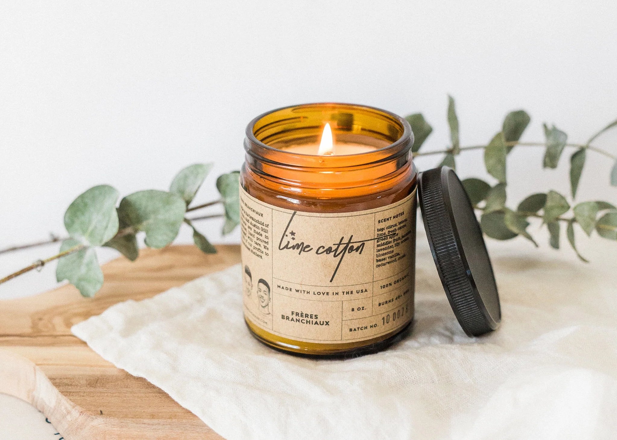 A lit candle is styles with a sprig of greenery