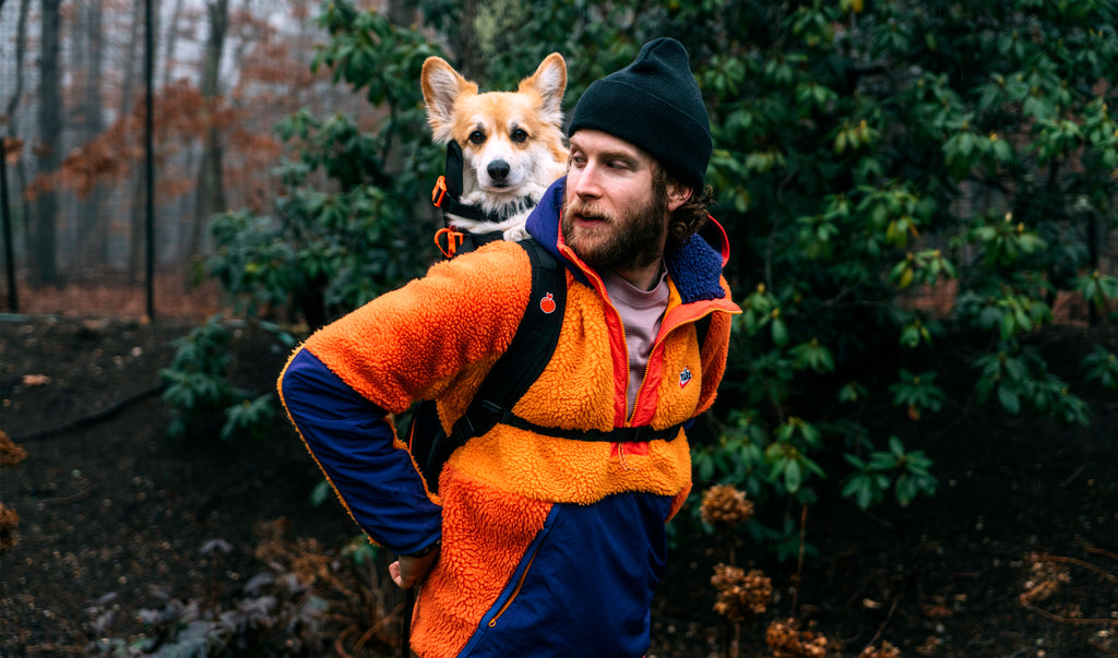 Little Chonk的联合创始人Bryan Reisberg穿着夹克站在那里，他的柯基犬Maxine在他背上的Little Chonk背包里。