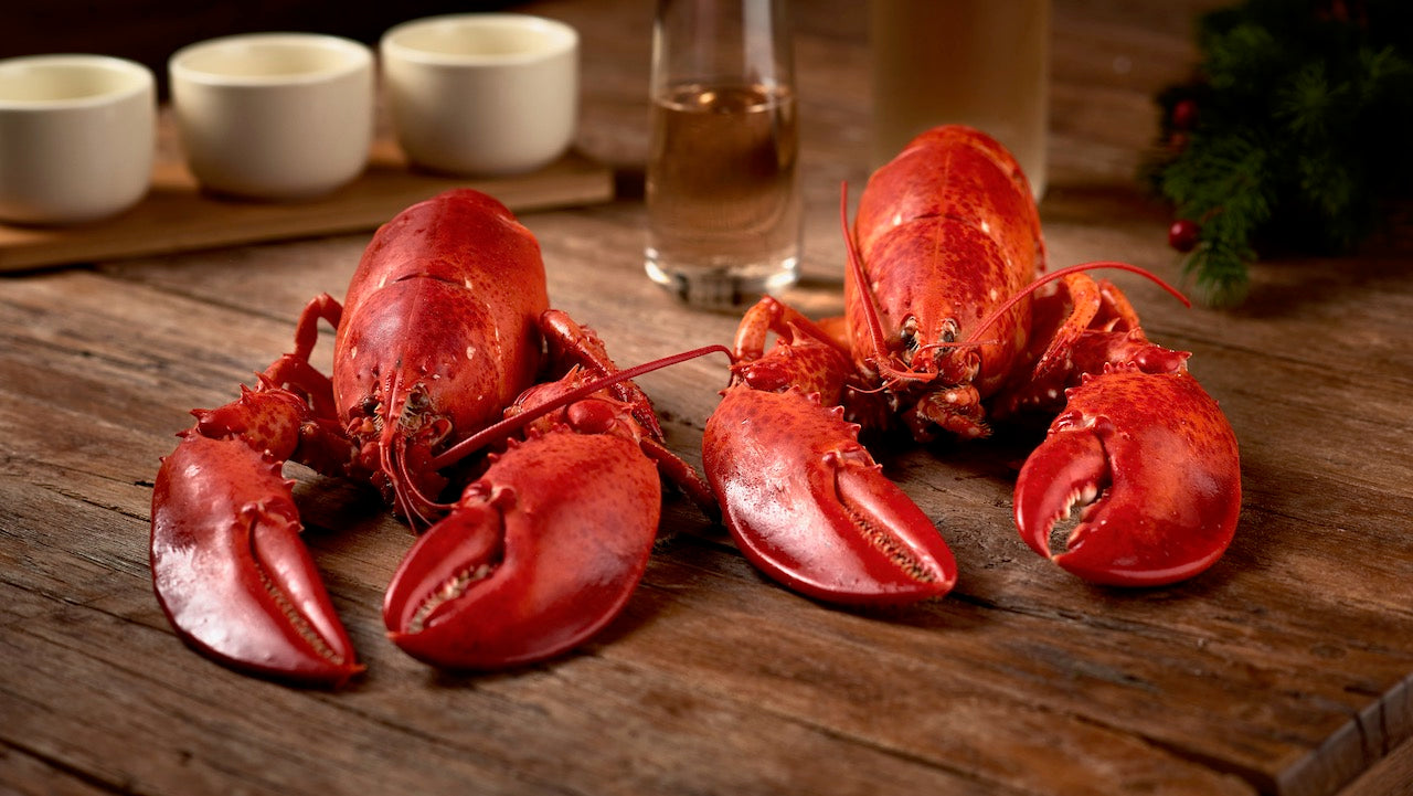 A pair of cooked lobsters on a wooden kitchen counter. 