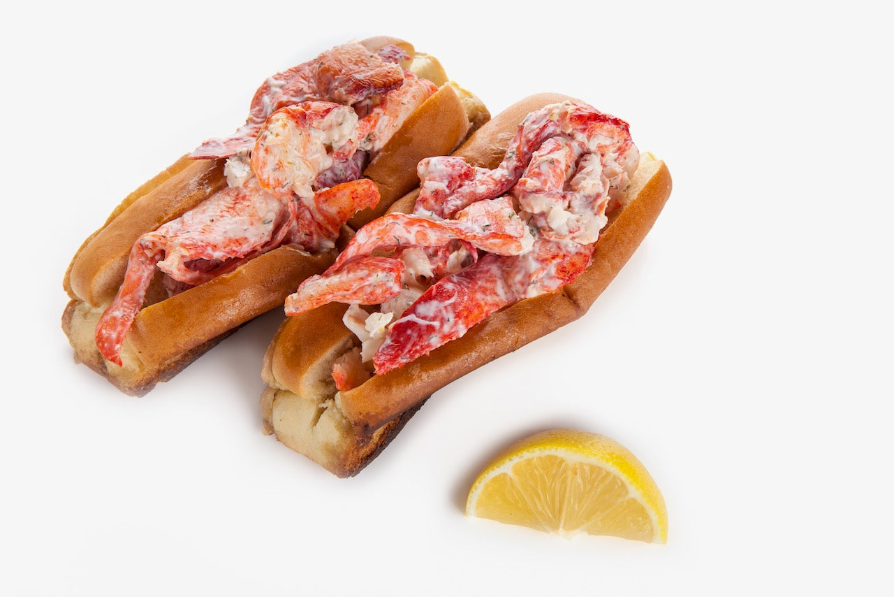  A pair of lobster rolls and a lemon wedge. 