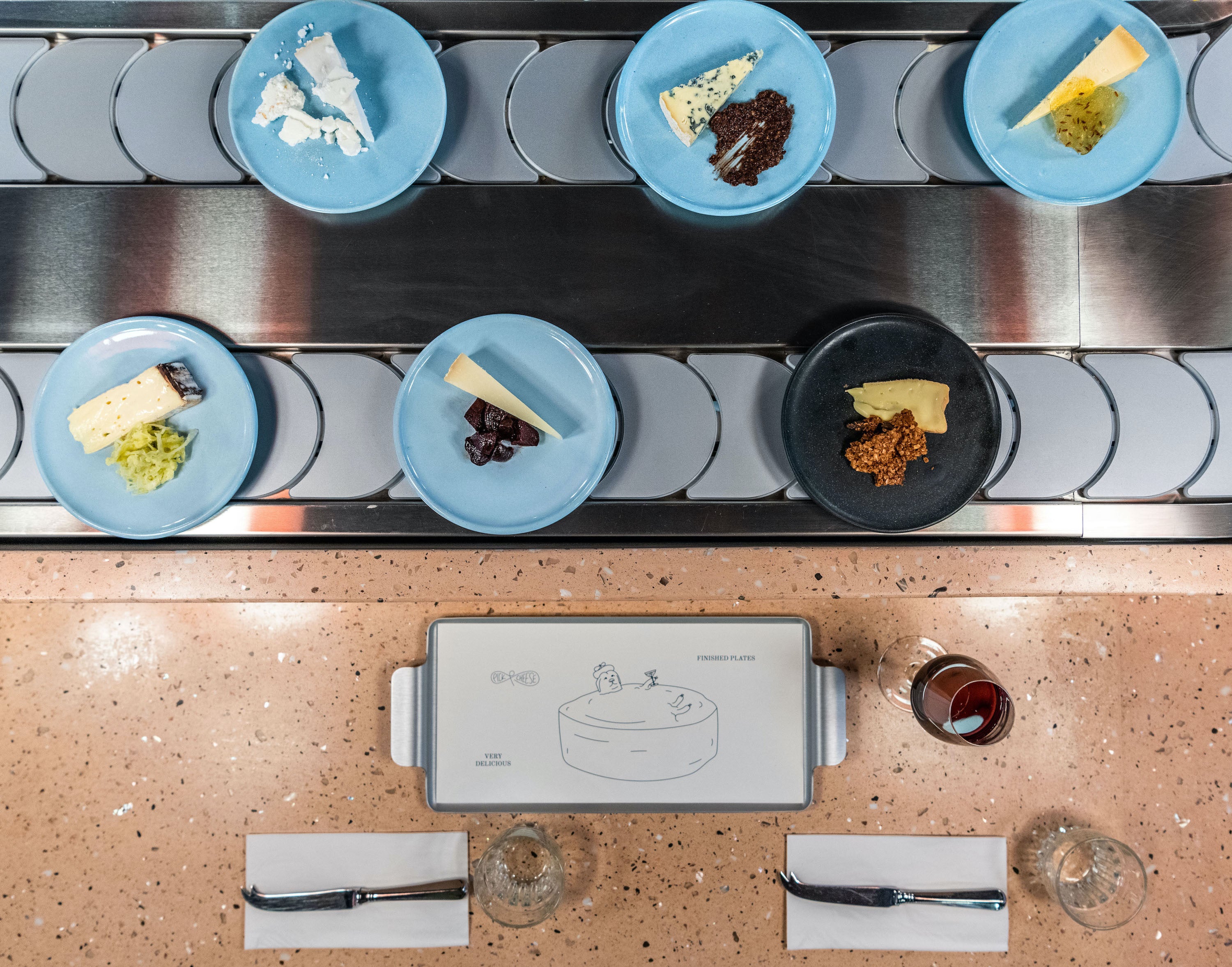 Various plates of cheese on a conveyor belt from a bird’s-eye view at the restaurant Pick & Cheese. 