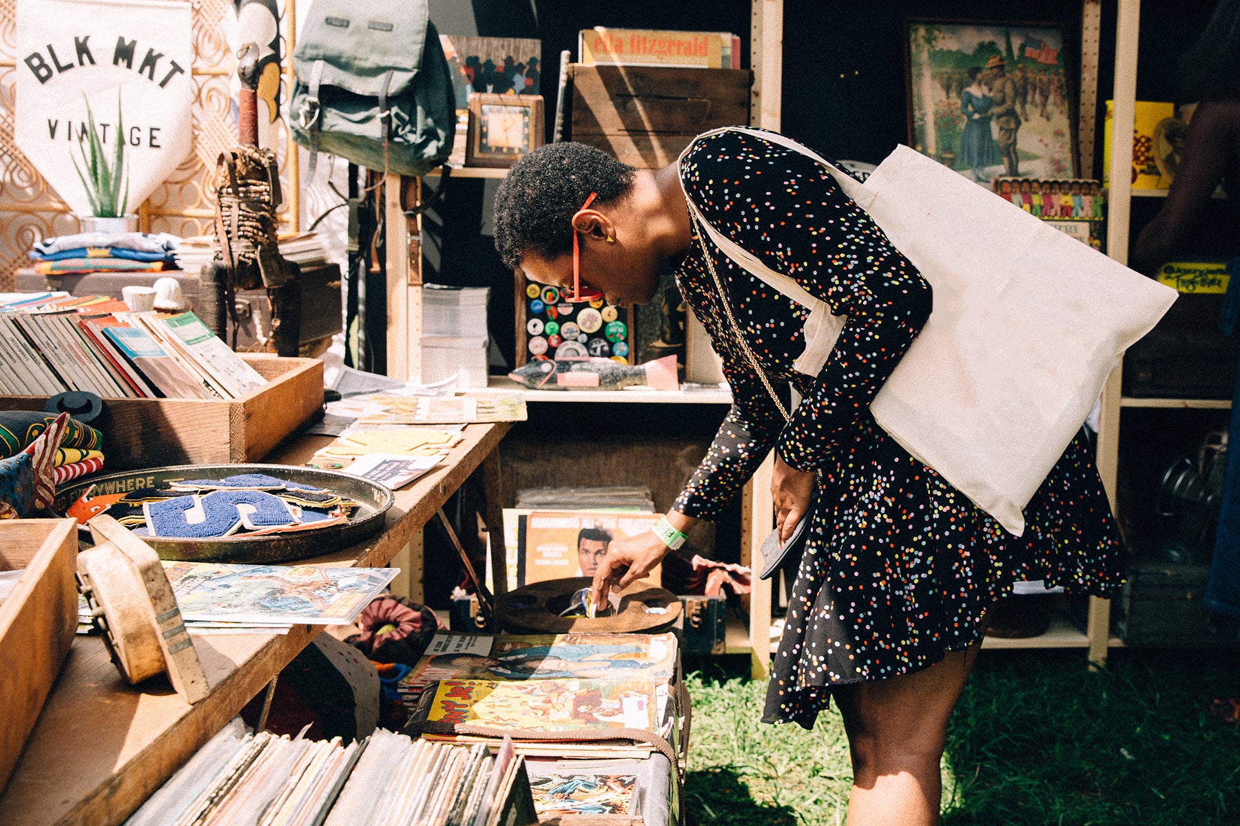 A woman in a black dress bends over to look at a retail display in BLK MKT Vintage's shop.