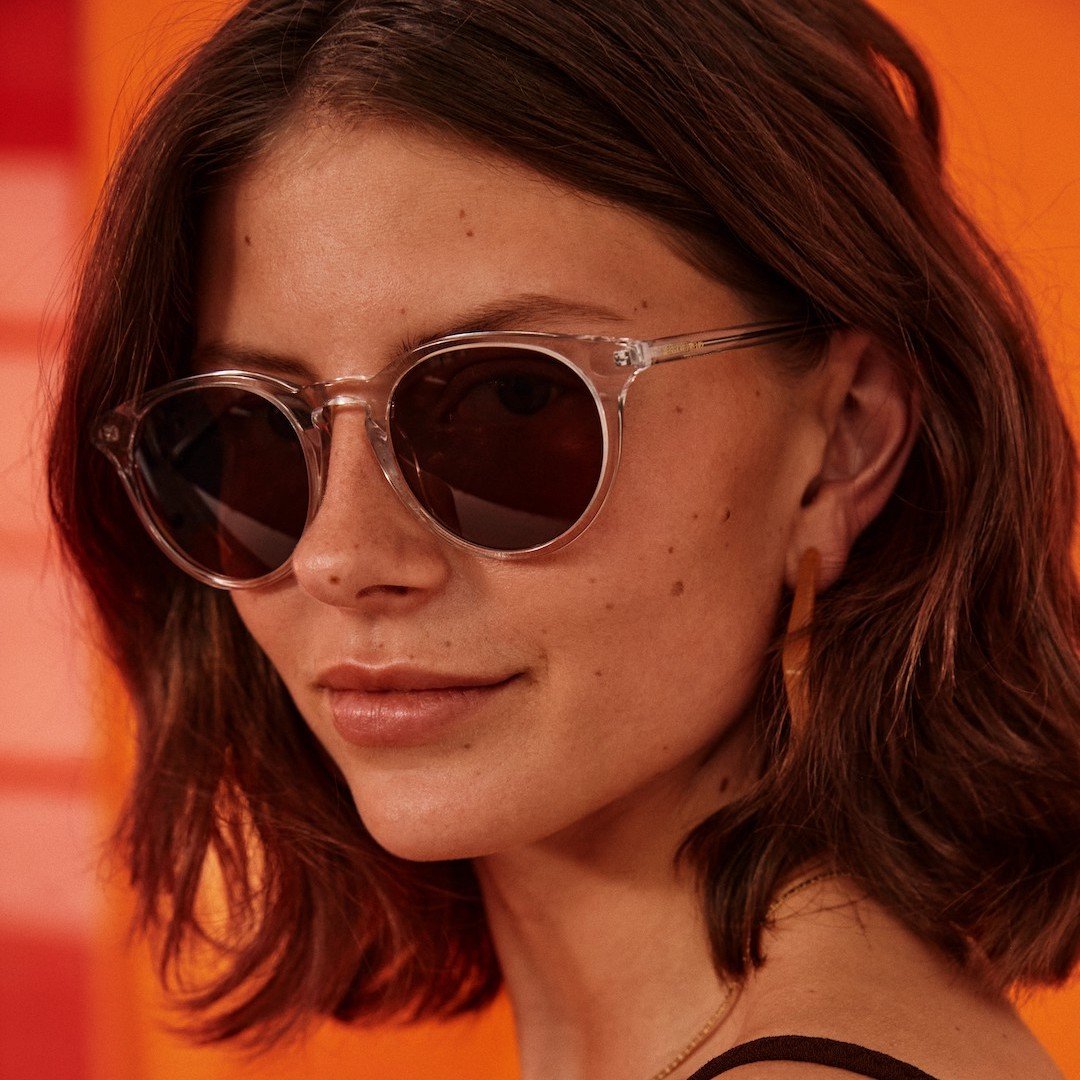 A model wearing a pair of clear framed sunglasses from MessyWeekend. 