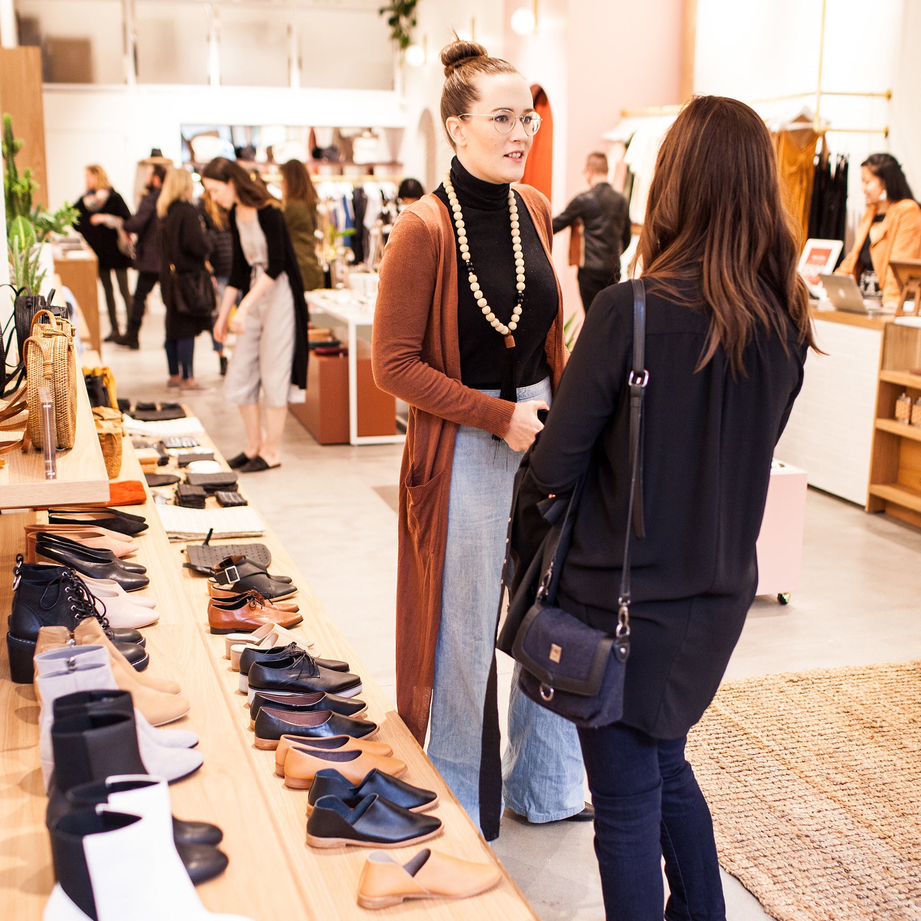 Moorea Seal talks to another woman in a busy store next to a shoe display