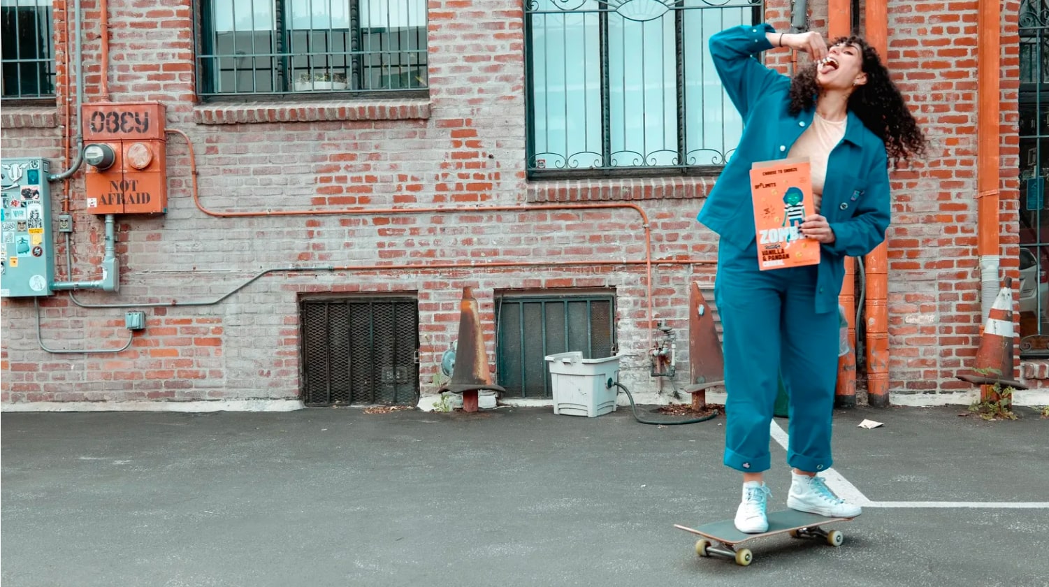 OffLimits founder Emily Miller skateboards in front of a brick building holding a box of Zombie cereal