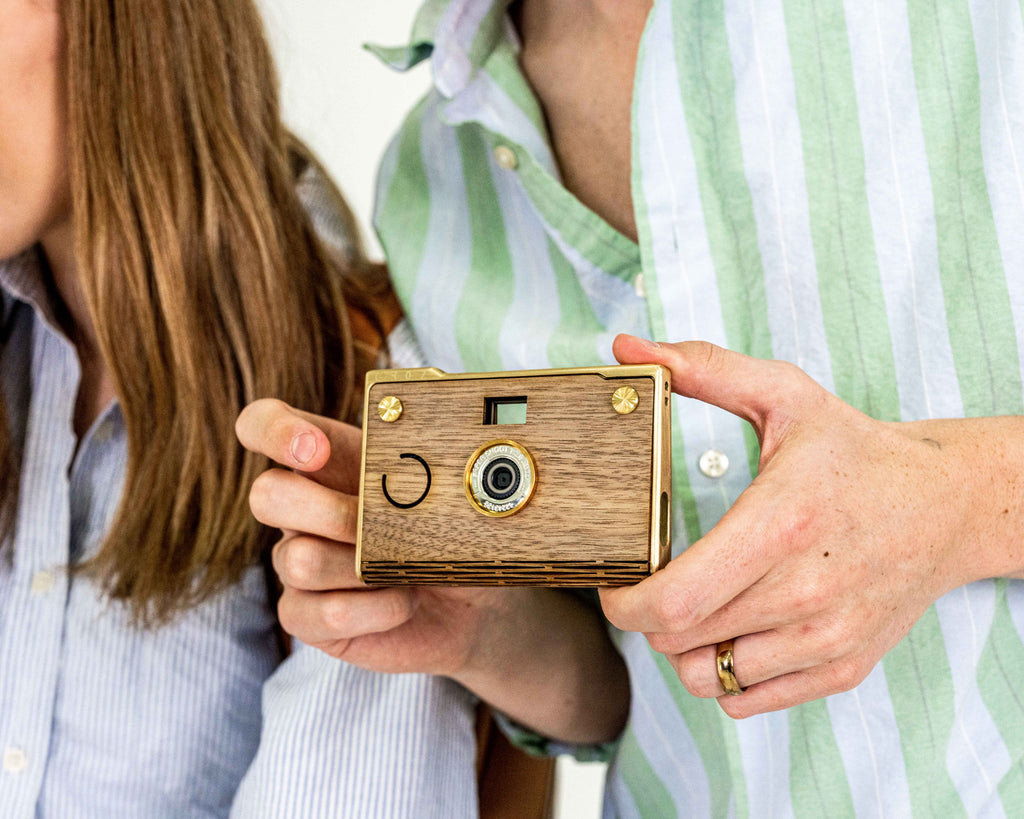 Man holding paper shoot camera next to woman