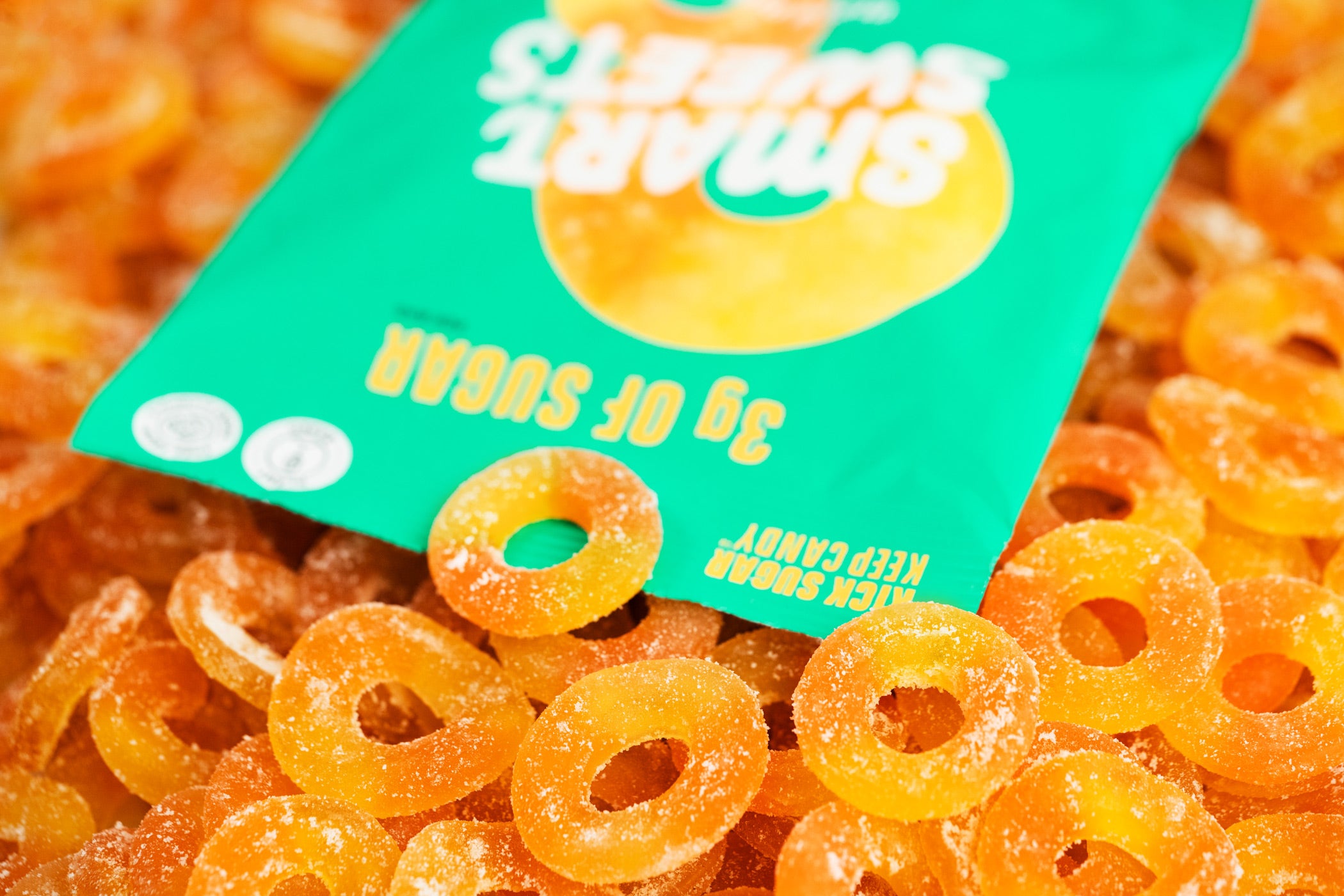 A bag of SmartSweets’ Peach Rings sitting on top of a pile of Peach Rings. 