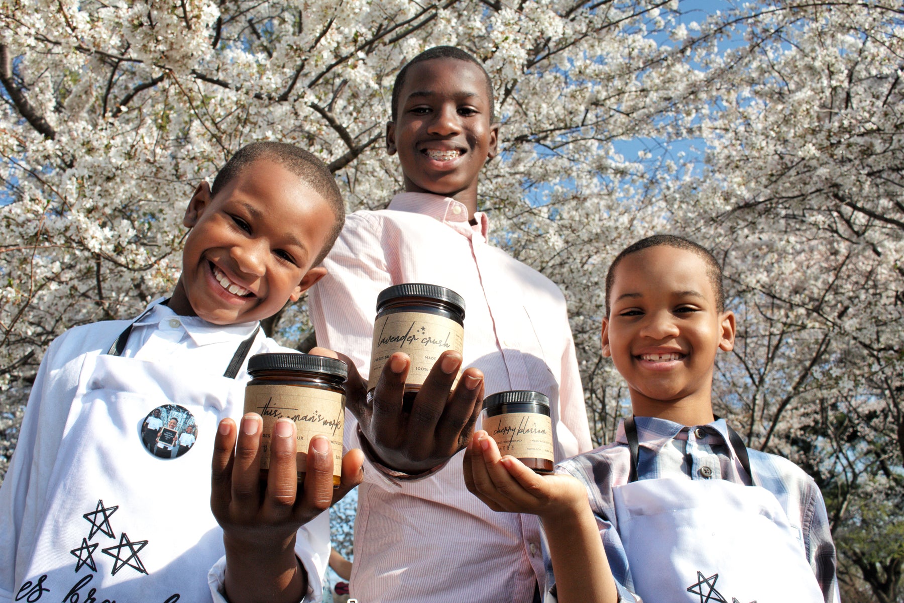 Portrait of Freres Branchiaux founders from left to right Ryan, Collin and Austin Gill standing under a cherry blossom tree, holding their handmade candles