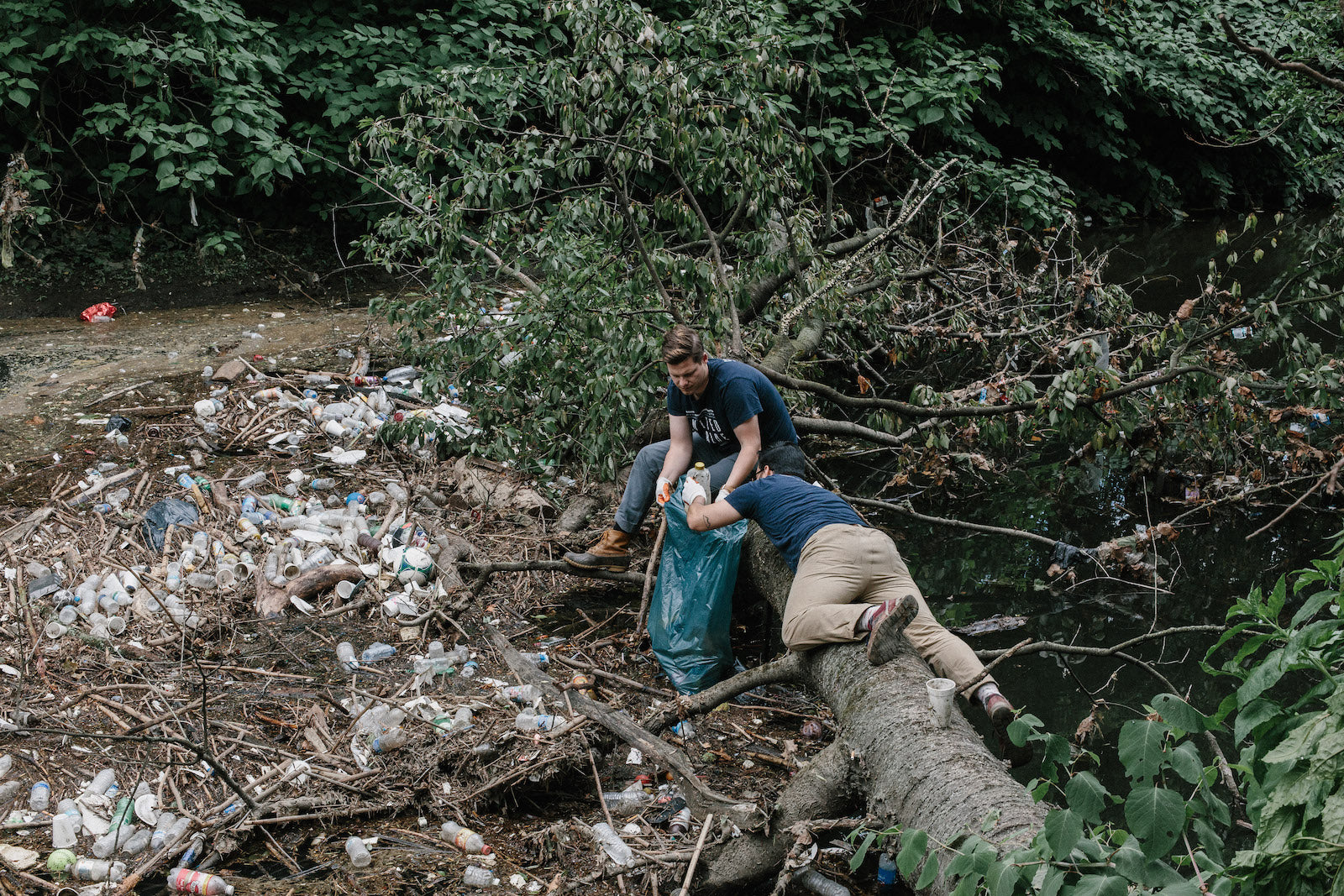 United By Blue co-founders Bryan and Mike collect trash from a riverside in their home city of Philadelphia.