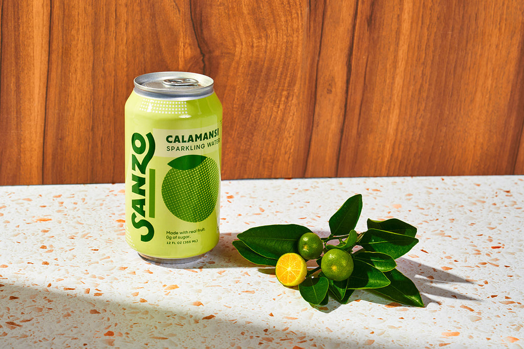 A can of Sanzo calamansi-flavored sparkling water next to calamansi fruit.