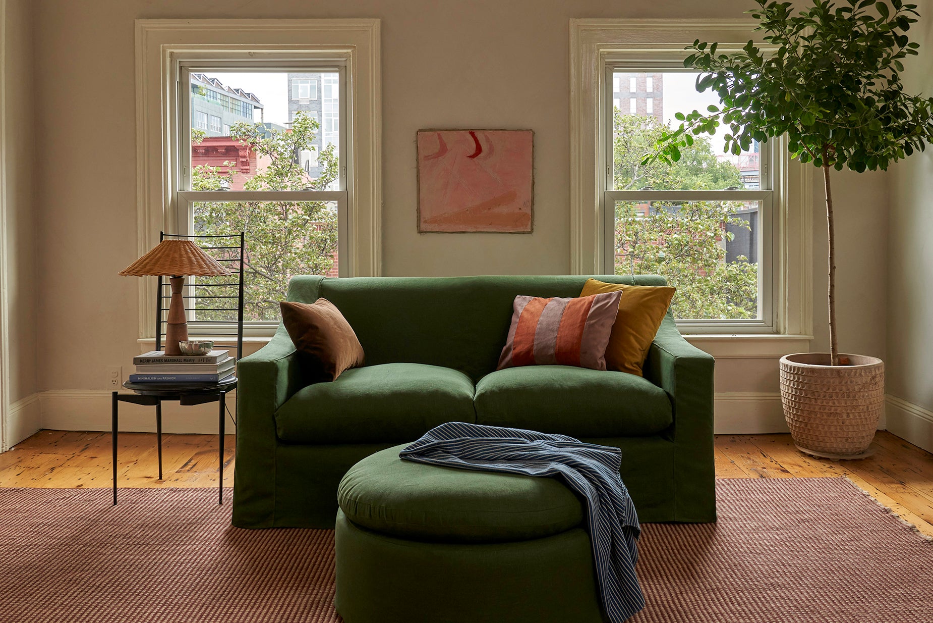 A green loveseat and ottoman in an apartment