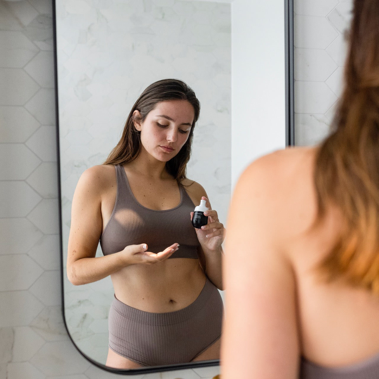 A model’s reflection in the mirror as she applies body oil from Bushbalm.