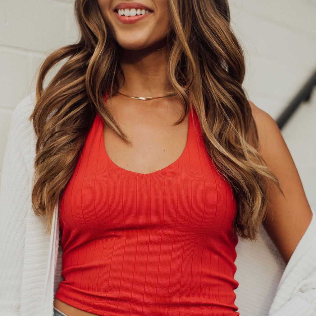 A model in a bright orange cami made by Klassy Network. 