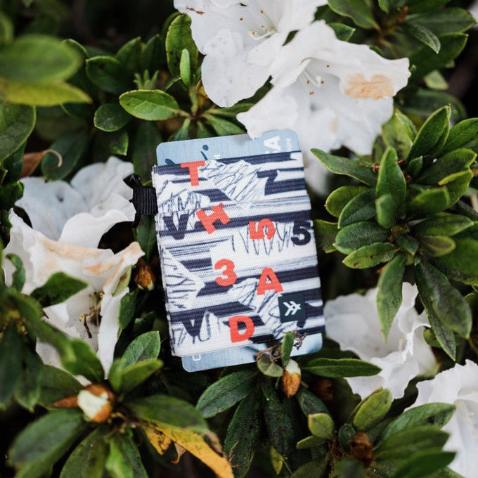 A colorful Thread Wallet on the backdrop of fresh flowers. 