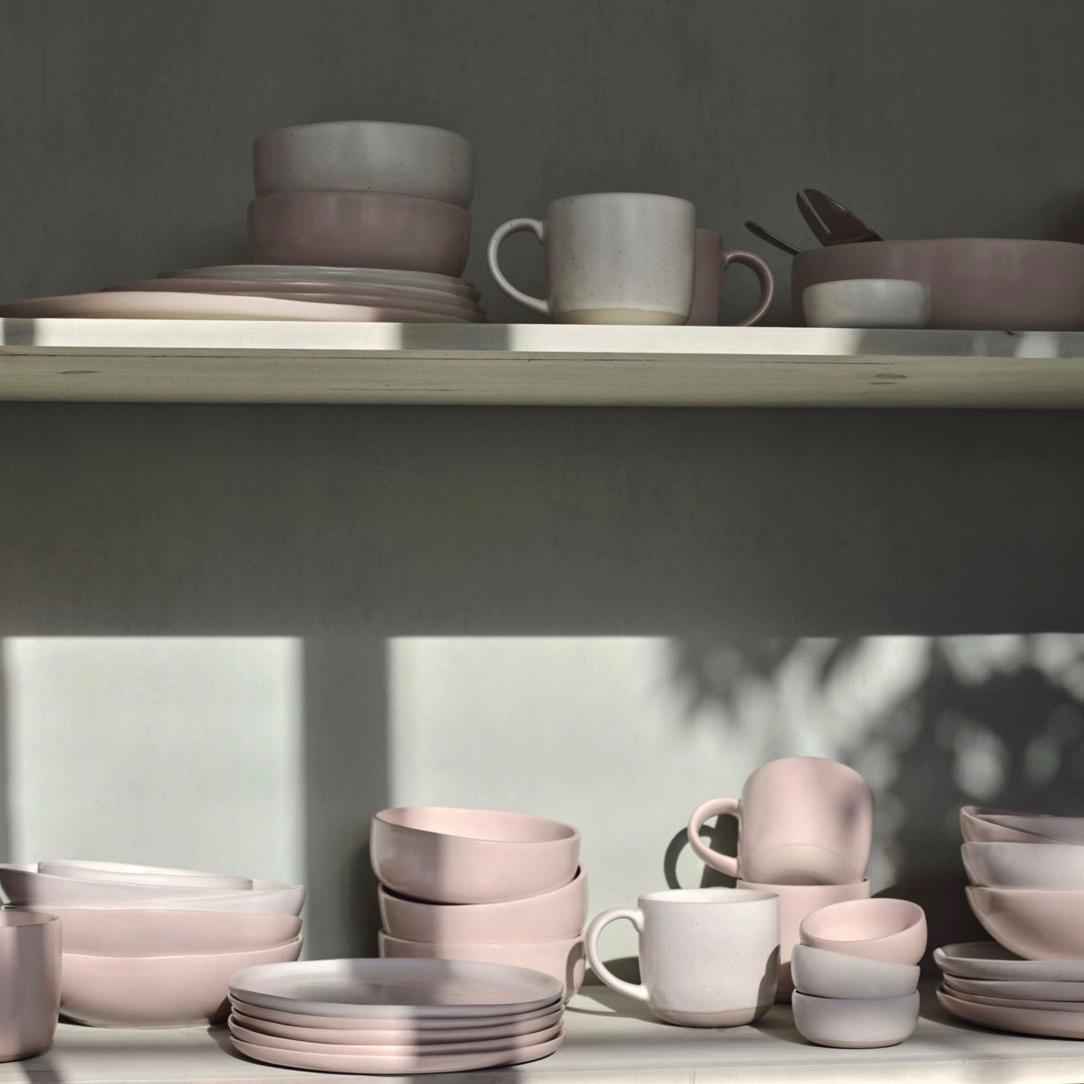 A shelf full of blush pink and speckled white dinnerware from Fable. 