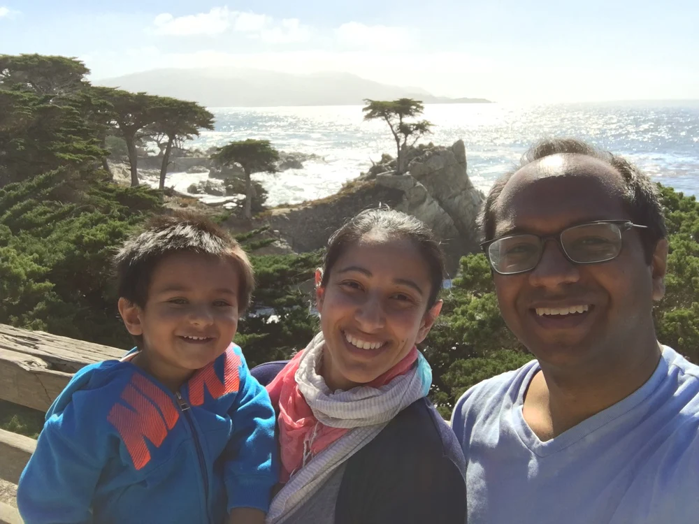 Aneela Idnani Kumar and Sameer Kumar, the life and business partners behind HabitAware along with their son backdropped by the ocean. 