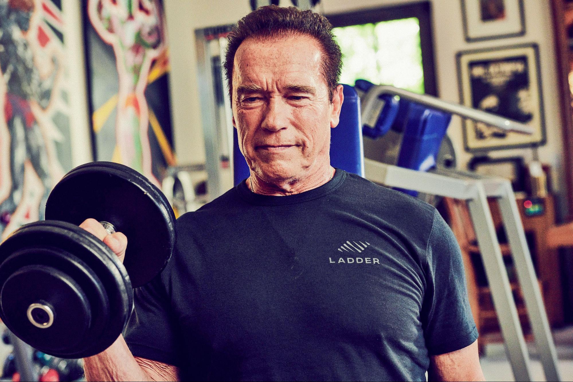 Arnold Schwarzenegger working out in a t-shirt with Ladder’s logo.