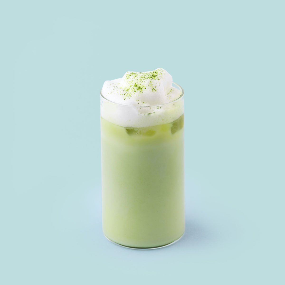 A glass of matcha latte with foam made with PureChimp’s matcha powder.