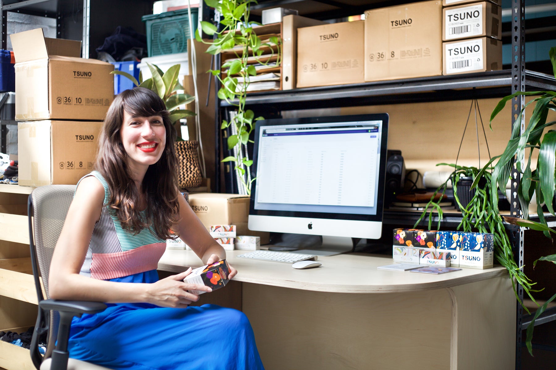 Roz Campbell, founder of Tsuno, smiling at her desk surrounded by inventory.
