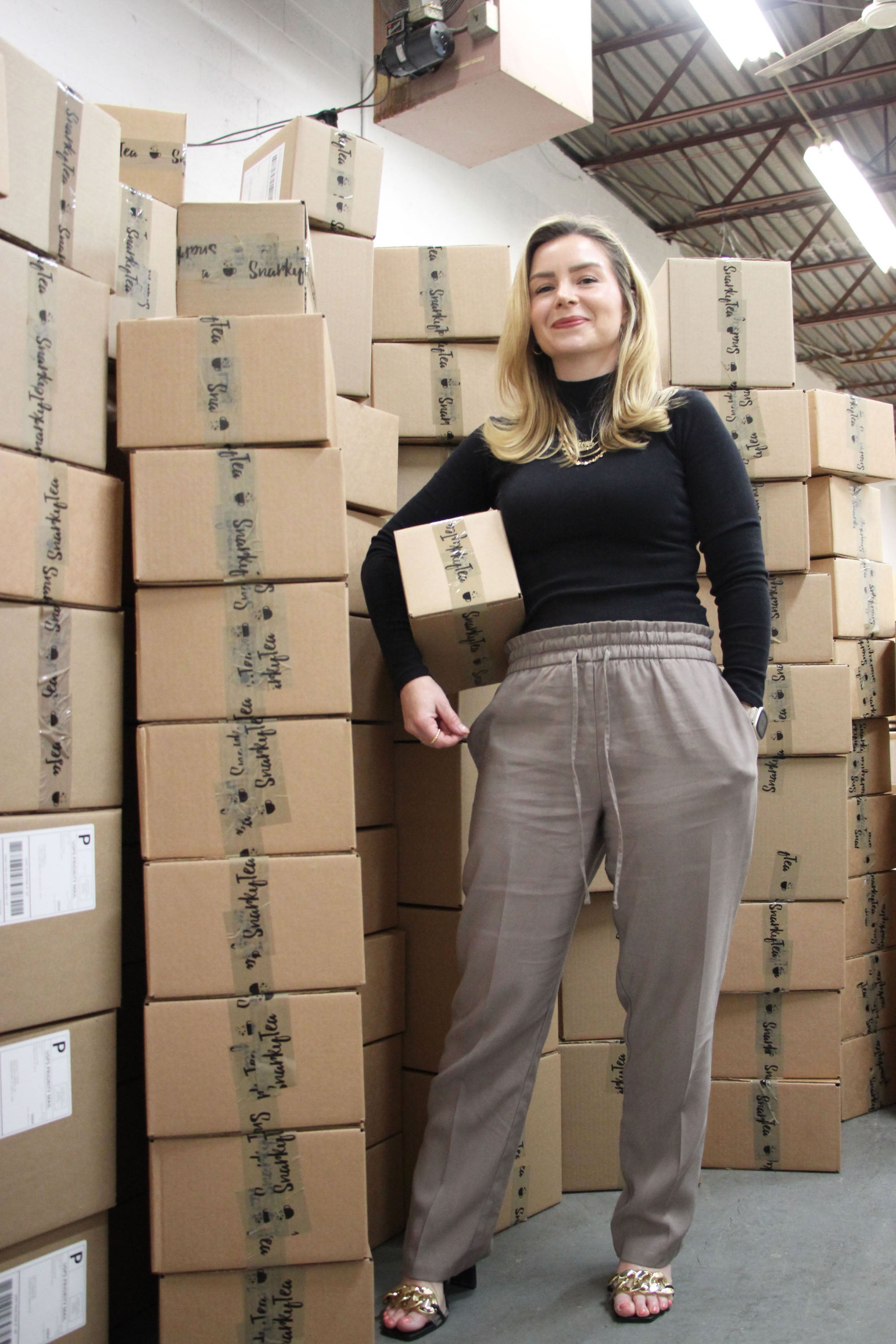 Jenni-Lyn Williams standing with a batch of orders ready to be picked up by USPS