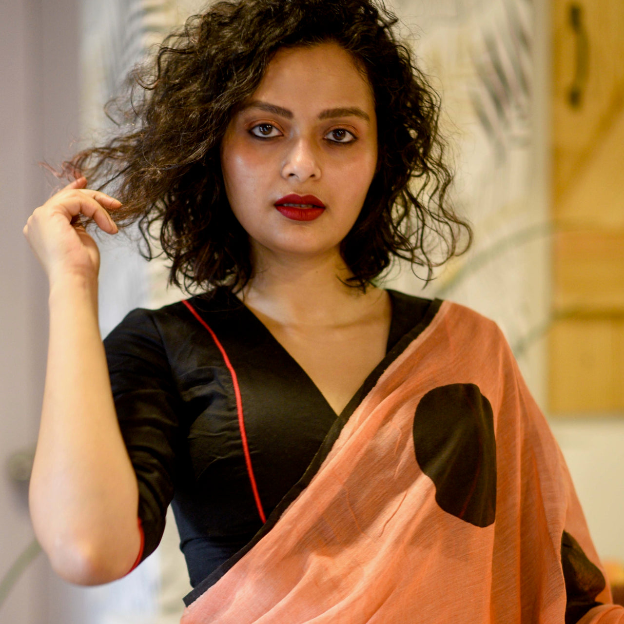 Sujata models a black blouse along with an orange saree with large black dots. 