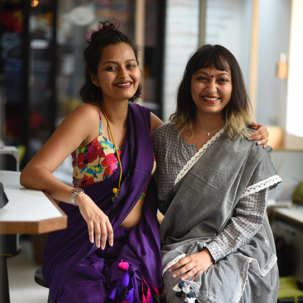  Sujata, in a purple saree and a flower-patterned top, sits with Taniya, in a gray saree with a checkered blouse. 